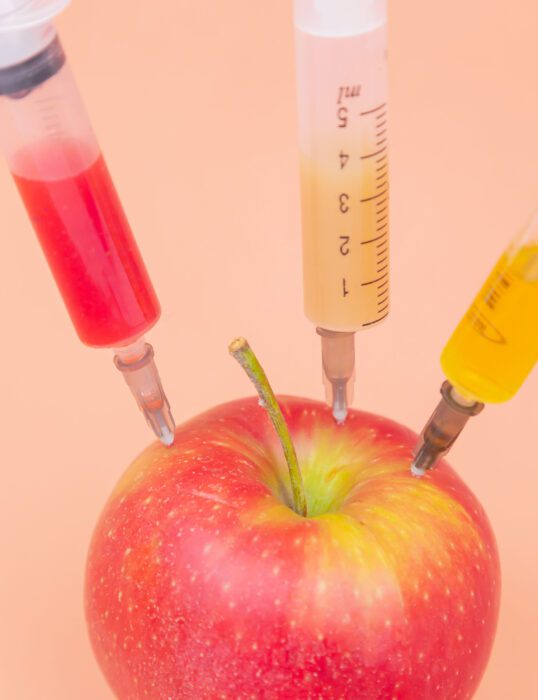Apple with three syringes stuck in it