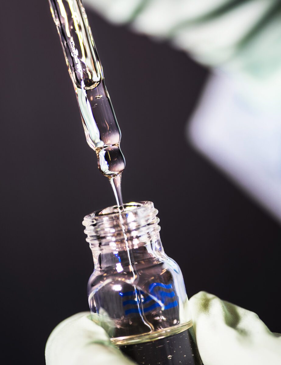 Gloved hand pulling a pipette out of a glass bottle