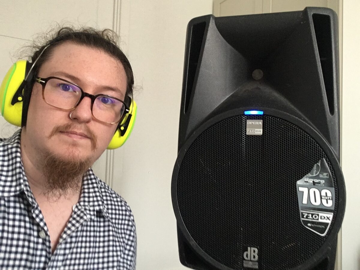 Baden wearing sound defender headphones standing next to a speaker