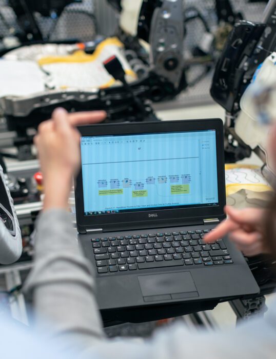 Person working on laptop and gesturing in front of screen