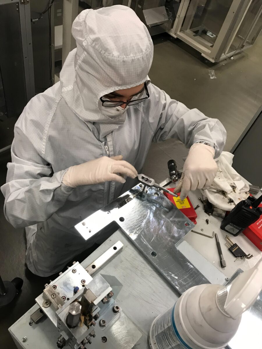 Engineer in protective clothing using tools to test machine
